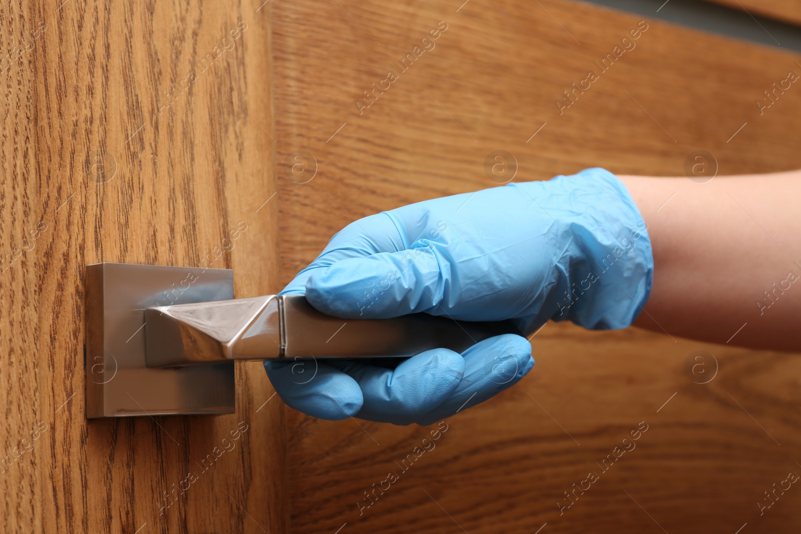 Photo of Woman in protective gloves opening wooden door, closeup