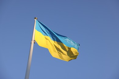 Photo of Flag of Ukraine fluttering against blue sky, low angle view