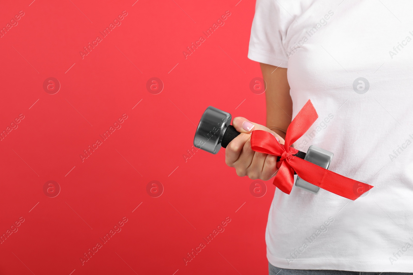 Photo of Closeup view of woman with dumbbell as girl power symbol on red background, space for text. 8 March concept