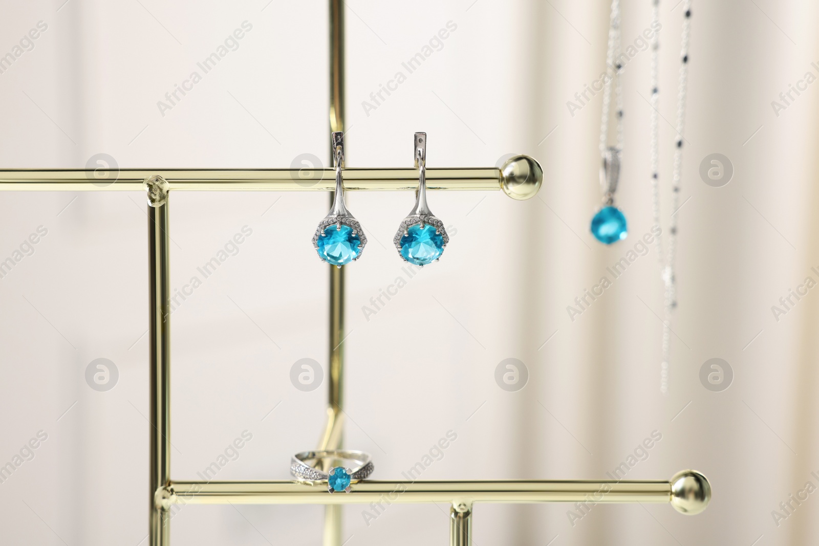 Photo of Beautiful jewelry with light blue gemstones on stand, closeup