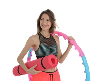 Beautiful woman with yoga mat and hula hoop on white background