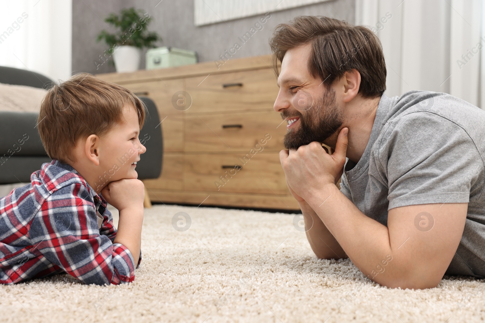 Photo of Happy dad and son looking at each other at home