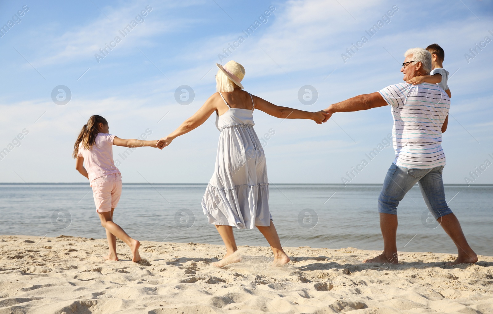 Photo of Cute little children with grandparents spending time together on sea beach