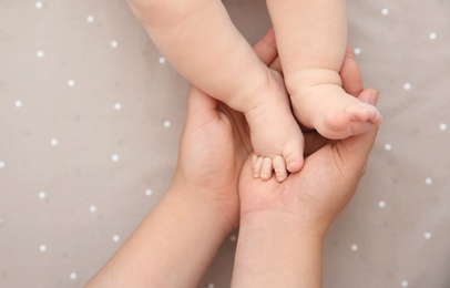 Photo of Mother holding little baby feet in hands, top view
