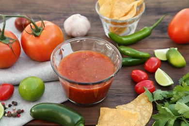 Tasty salsa sauce and different ingredients on wooden table, closeup