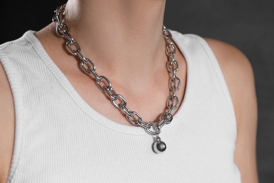 Photo of Woman wearing metal chain with pendant on grey background, closeup. Luxury jewelry