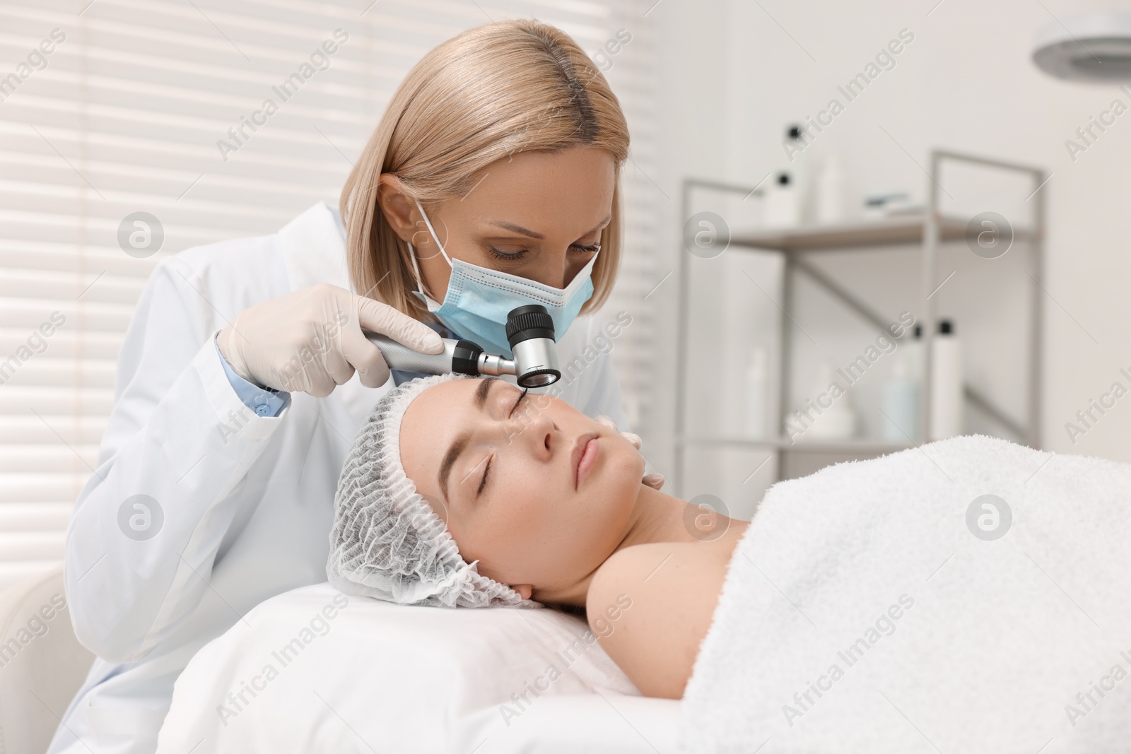 Photo of Dermatologist with dermatoscope examining patient`s face in clinic