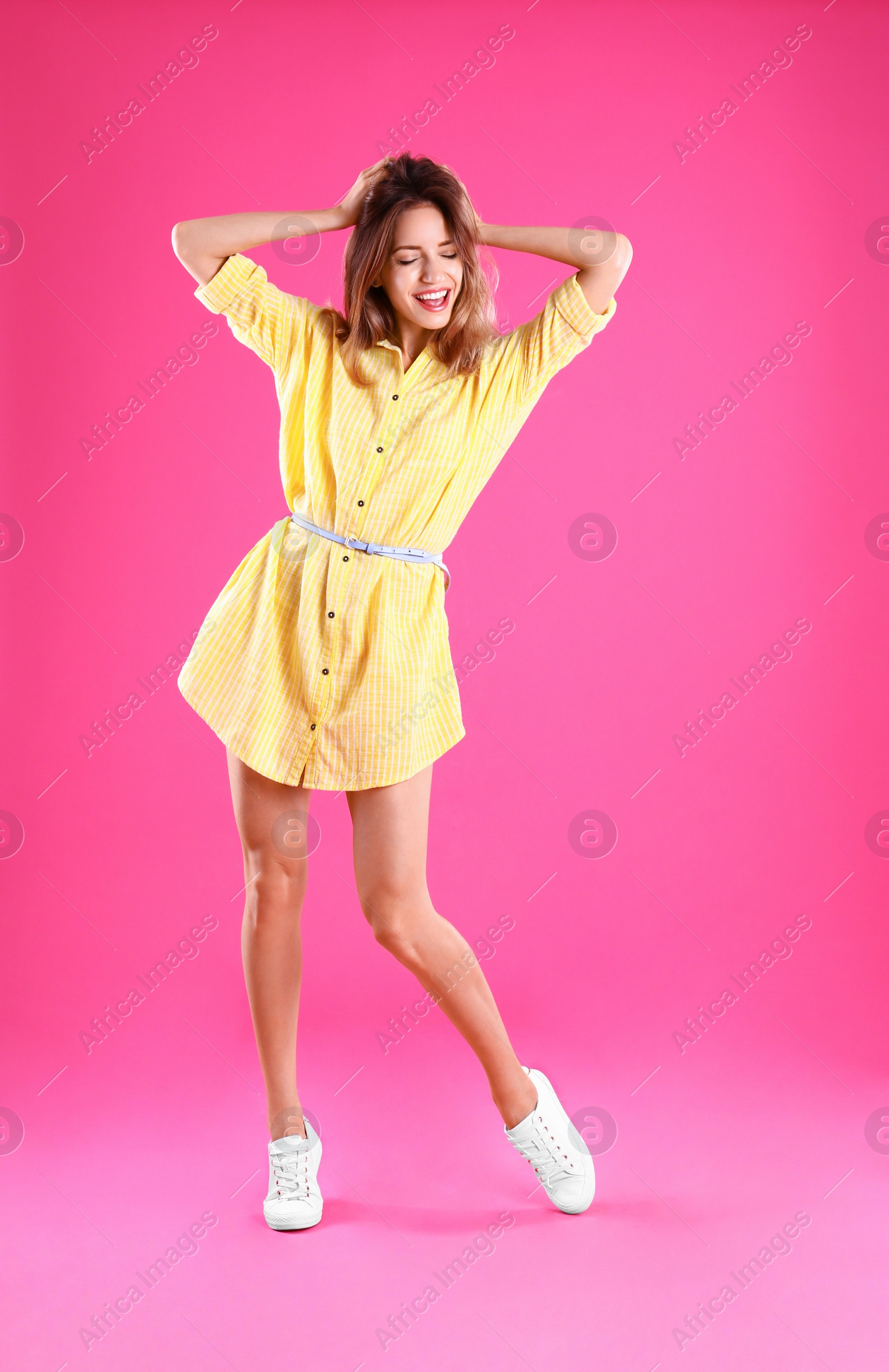 Photo of Beautiful young woman in yellow dress dancing on pink background