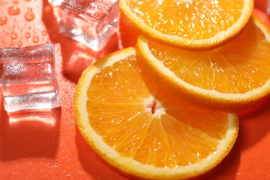 Slices of juicy orange and ice cubes on terracotta background, closeup
