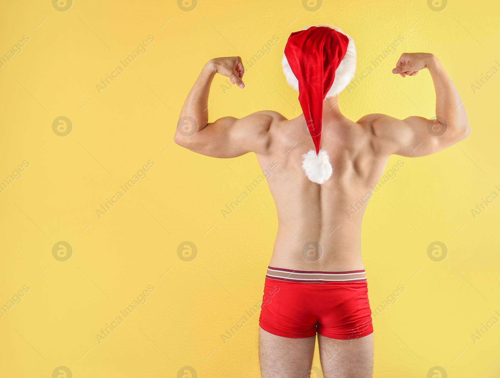 Photo of Shirtless young Santa Claus with sexy body on color background