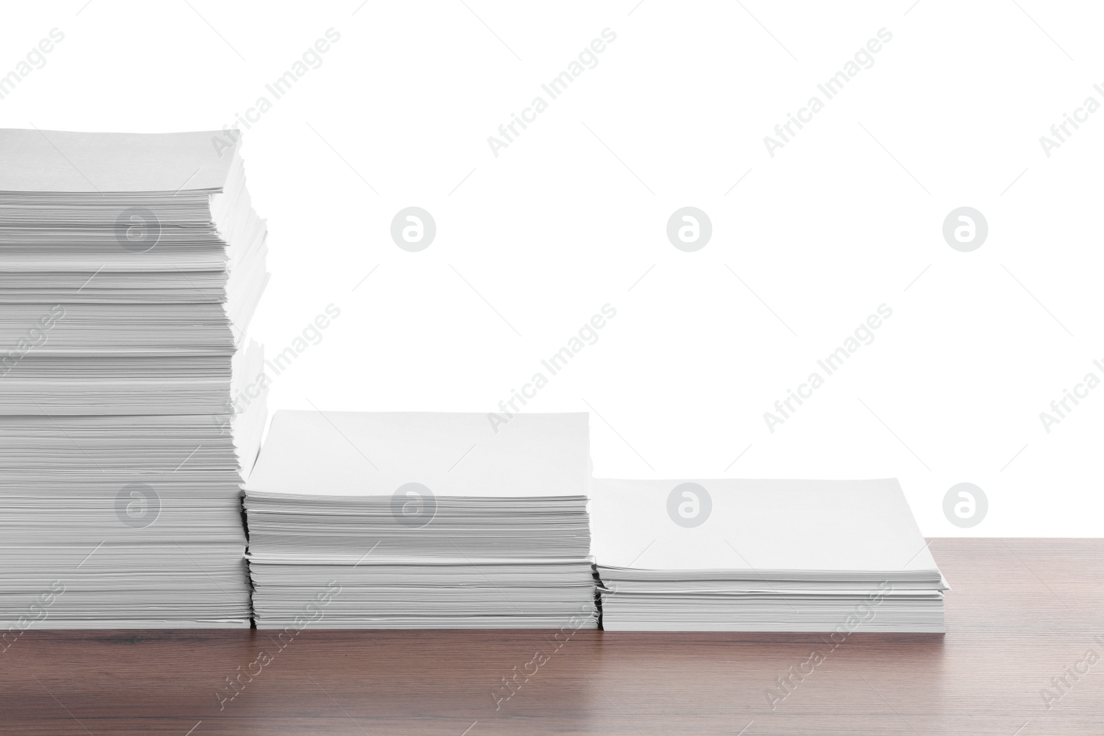 Photo of Stacks of paper sheets on wooden table against white background