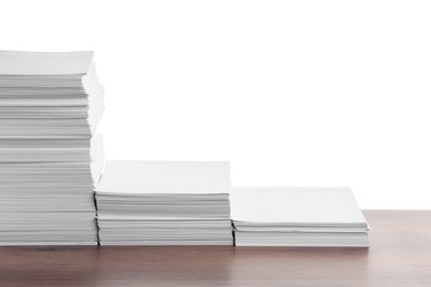 Stacks of paper sheets on wooden table against white background