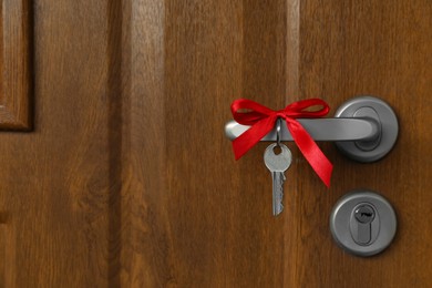 House key with red bow on door handle, closeup. Housewarming party