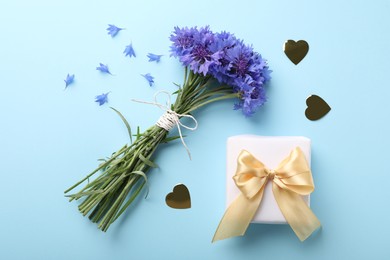 Photo of Bouquet of beautiful cornflowers and gift box on turquoise background, flat lay