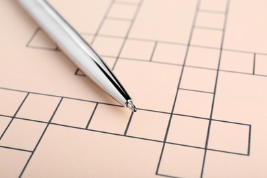 Photo of Pen on blank crossword, closeup. Intellectual entertainment