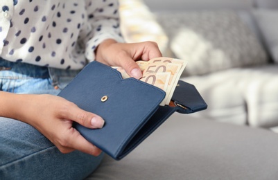Photo of Woman putting Euro banknotes in wallet, closeup