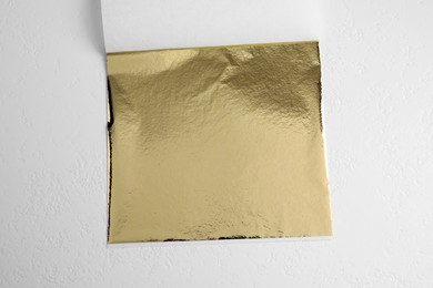 Edible gold leaf sheet on white background, top view
