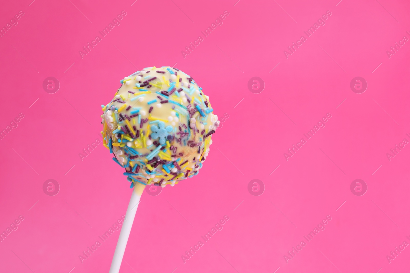 Photo of Delicious confectionery. Sweet cake pop decorated with sprinkles on pink background, closeup. Space for text