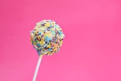 Photo of Delicious confectionery. Sweet cake pop decorated with sprinkles on pink background, closeup. Space for text