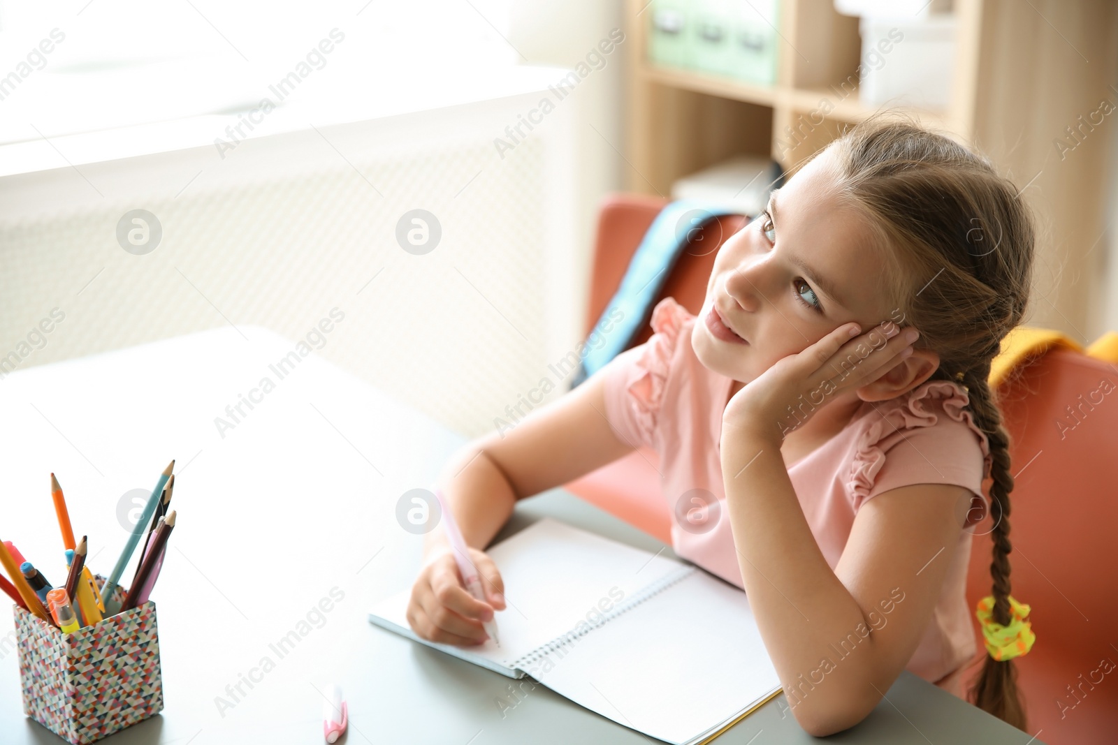 Photo of Cute little child daydreaming at desk in classroom. Elementary school