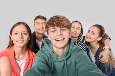 Photo of Group of happy teenagers taking selfie on light grey background