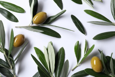 Fresh green olives and leaves on white background, flat lay