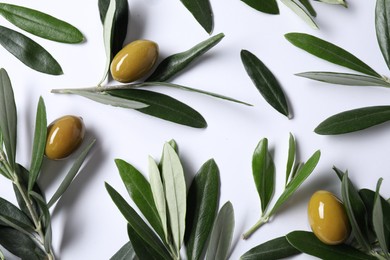 Photo of Fresh green olives and leaves on white background, flat lay