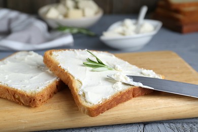 Photo of Delicious toasts with tofu cream cheese and rosemary on wooden board, closeup