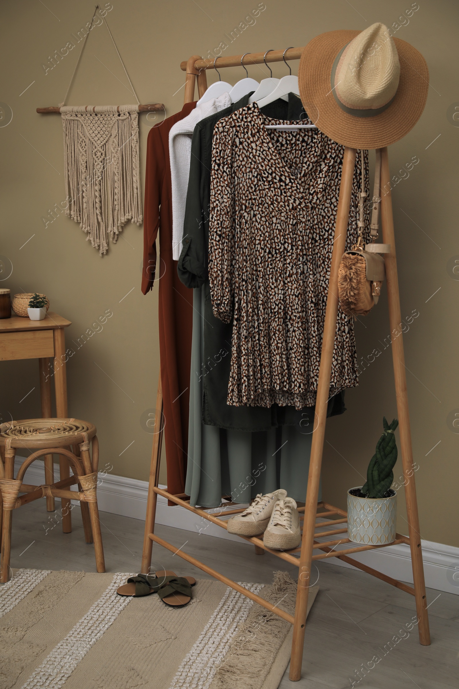 Photo of Modern dressing room interior with clothing rack and wooden table