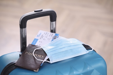 Photo of Passport, protective mask and tickets on blue suitcase. Travel during quarantine
