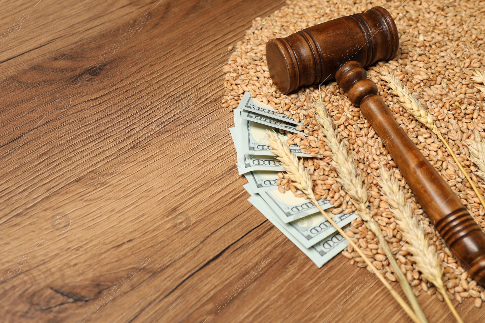 Photo of Dollar banknotes, judge's gavel, wheat ears and grains on wooden table, space for text. Agricultural business