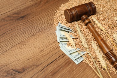 Dollar banknotes, judge's gavel, wheat ears and grains on wooden table, space for text. Agricultural business