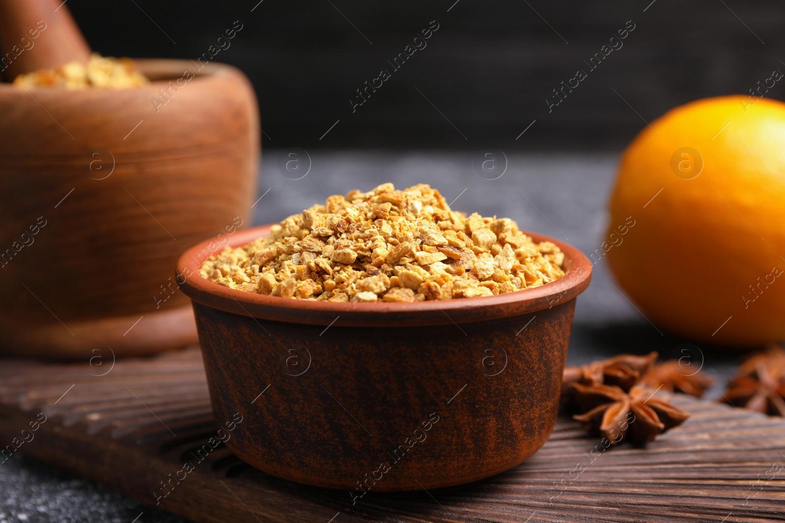 Photo of Bowl of dried orange zest seasoning, fresh fruit and anise on grey table