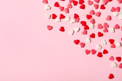 Heart shaped sprinkles on pink background, flat lay. Space for text