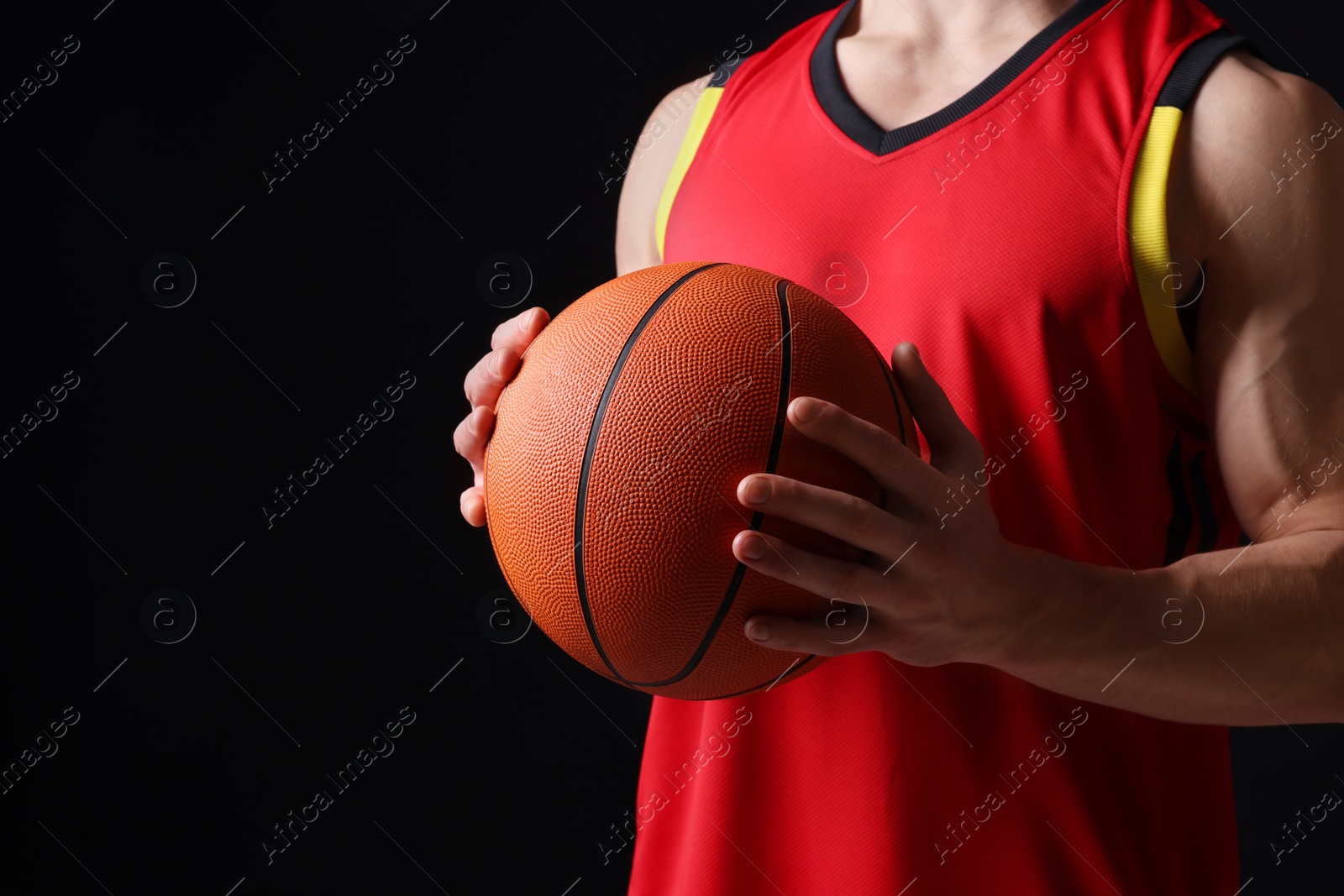 Photo of Athletic man with basketball ball on black background, closeup. Space for text