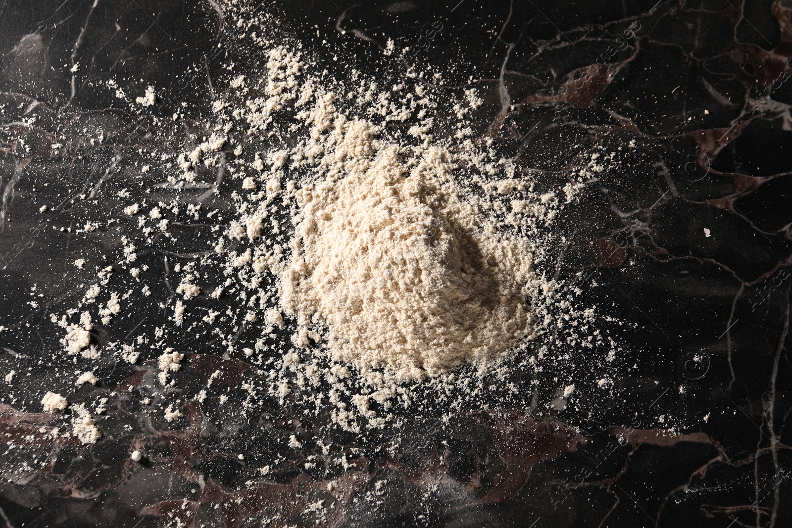 Photo of Pile of flour on black marble table, top view