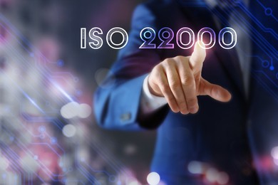 Man pointing at virtual screen with text ISO 22000, closeup