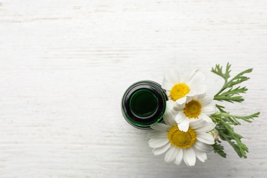 Photo of Flat lay composition with bottle of chamomile essential oil and space for text on white wooden background