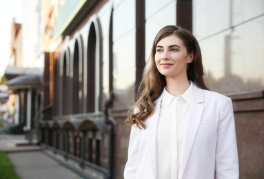 Photo of Young businesswoman near modern building on city street