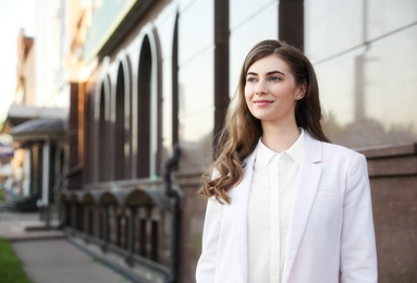 Young businesswoman near modern building on city street