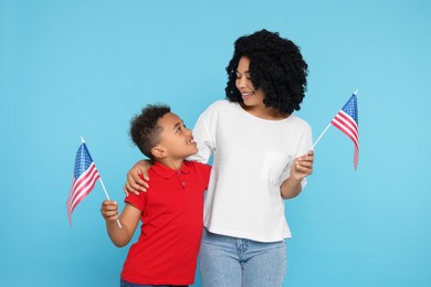 Photo of 4th of July - Independence Day of USA. Happy woman and her son with American flags on light blue background