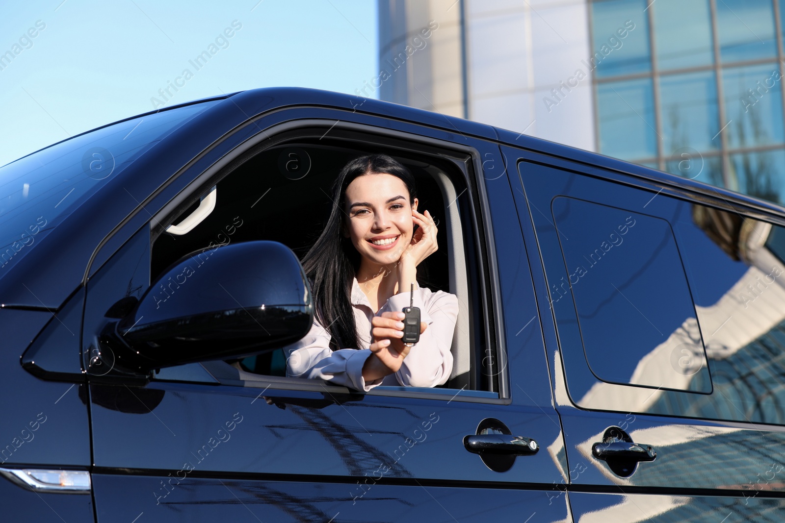 Photo of Young woman with key sitting in car outdoors. Buying new auto