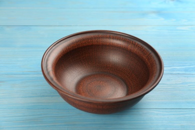 Photo of Clay bowl on light blue wooden table