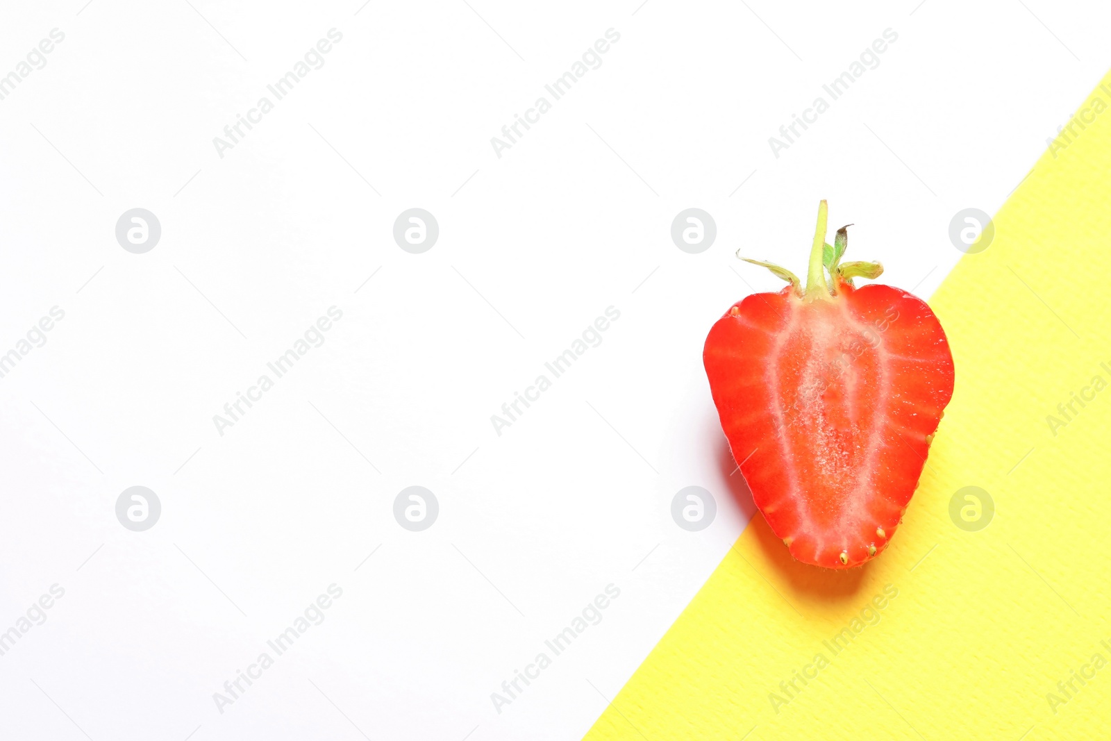 Photo of Half of ripe strawberry on color background, top view