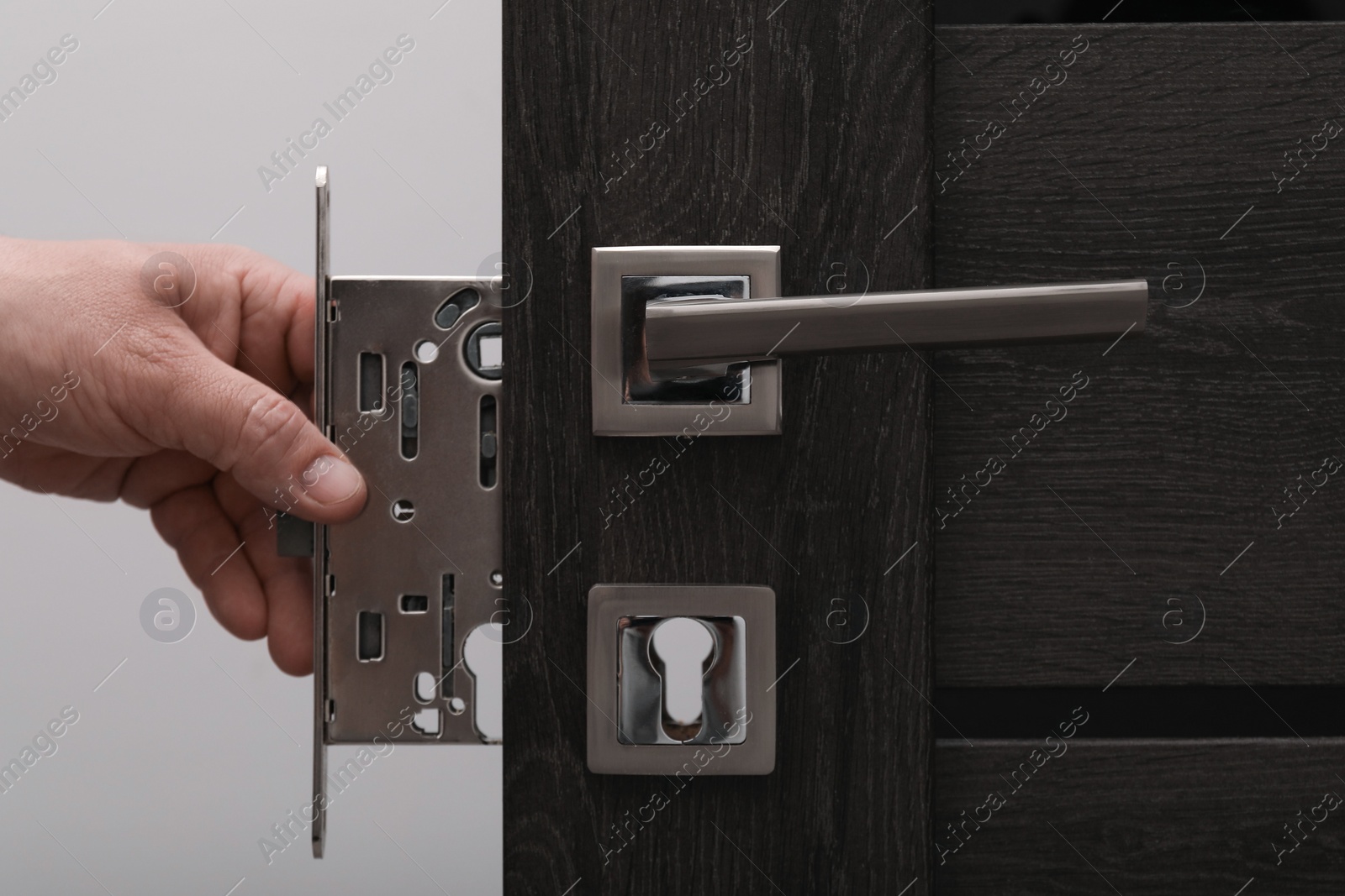 Photo of Handyman changing door handleset indoors, closeup view