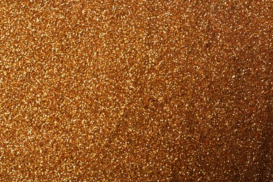 Photo of Beautiful shiny bronze glitter as background, closeup