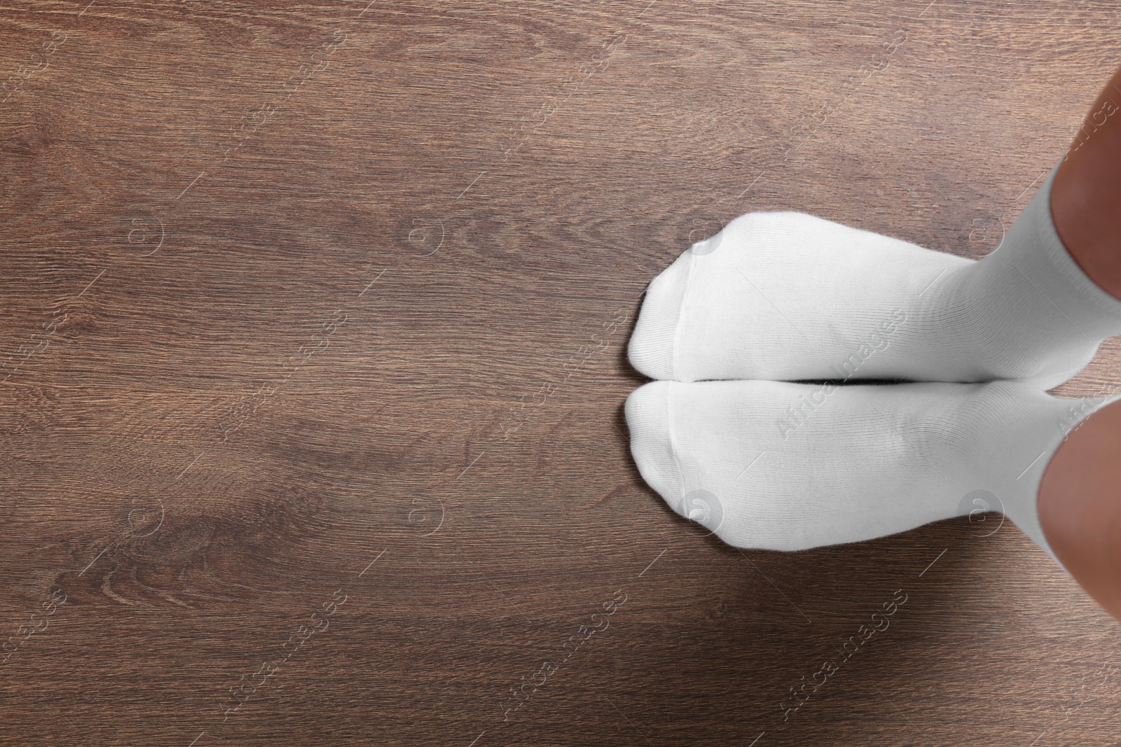 Photo of Woman in stylish white socks standing on wooden floor, top view. Space for text