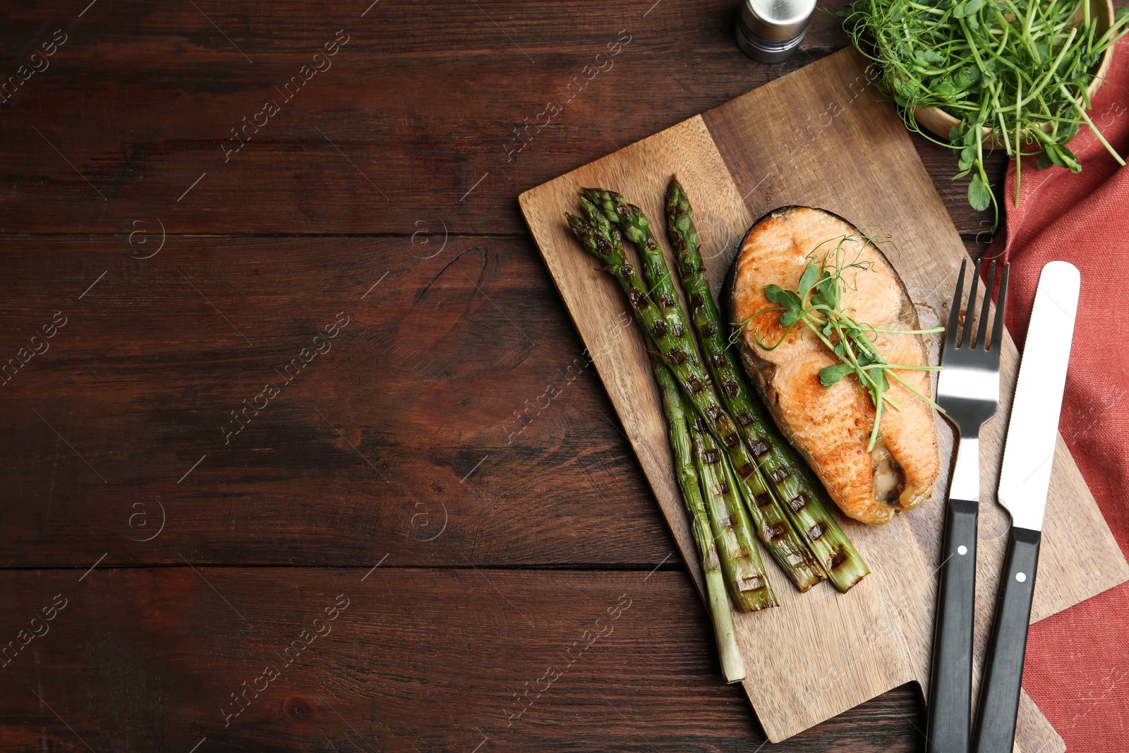 Photo of Tasty salmon steak served with asparagus and sprouts on wooden table, flat lay. Space for text