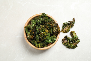 Tasty baked kale chips on grey marble table, flat lay