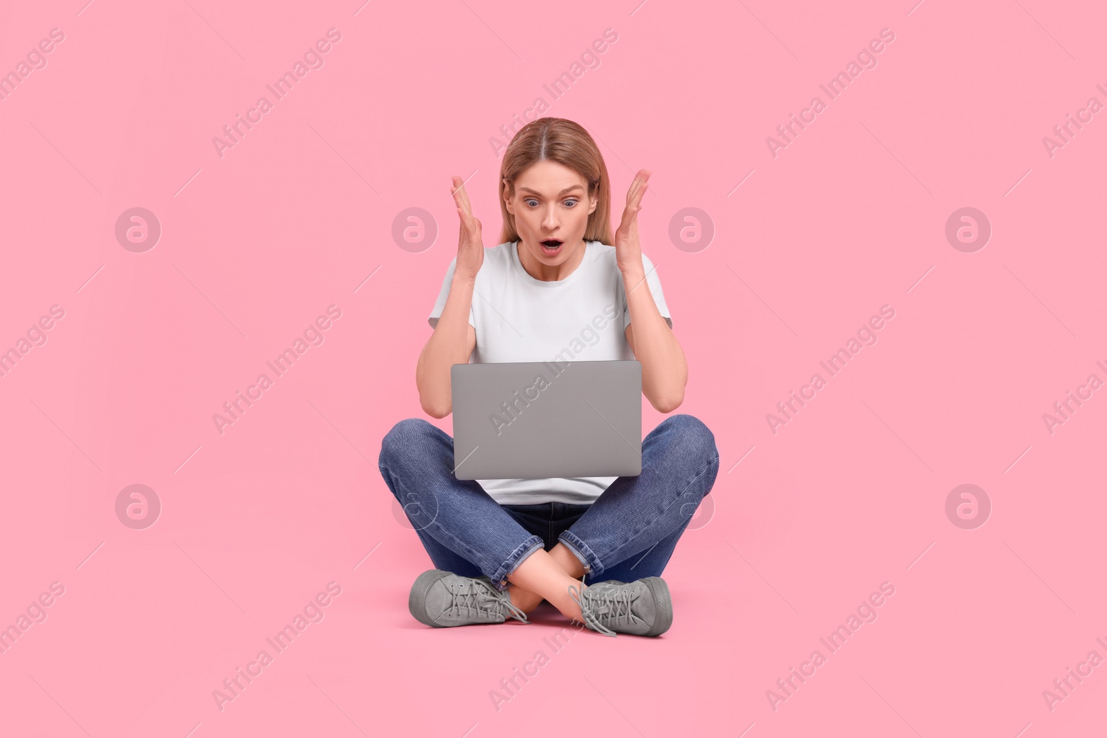 Photo of Emotional woman with laptop on pink background